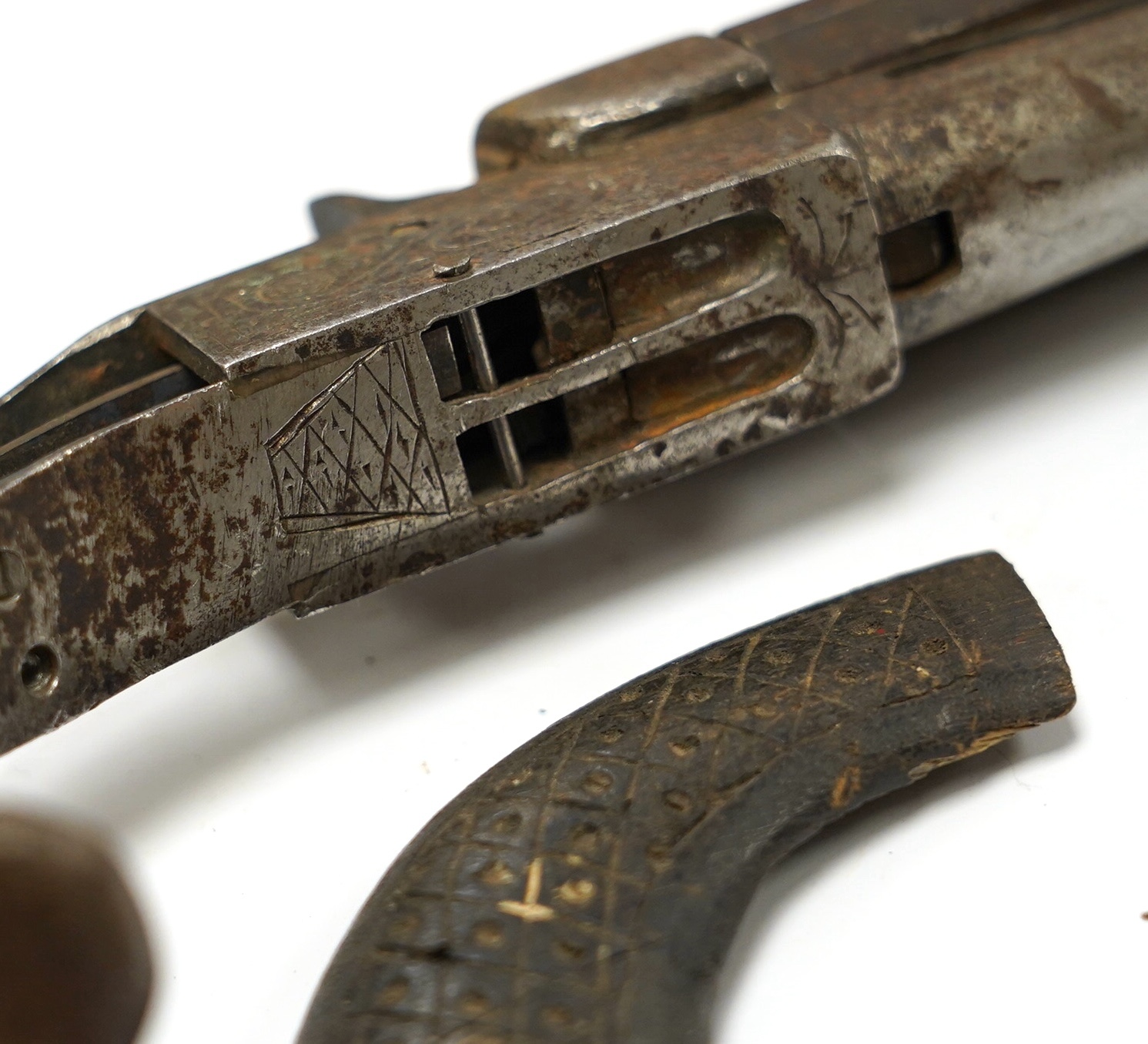 An early 19th century double-barrelled breach loading percussion pistol in relic condition, steel barrels, engraved frame, and walnut two piece grip, one piece missing, one piece detached, folding triggers, both missing